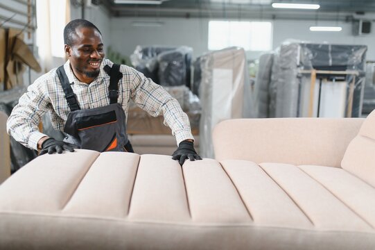 African american Furniture maker upholstering sofa in factory warehouse