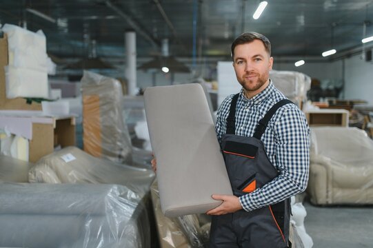 Furniture maker holding sofa cushion in factory warehouse