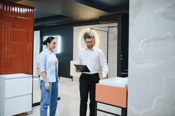 Fototapeta premium Shop assistant showing a sink to a customer in a bathroom furniture store