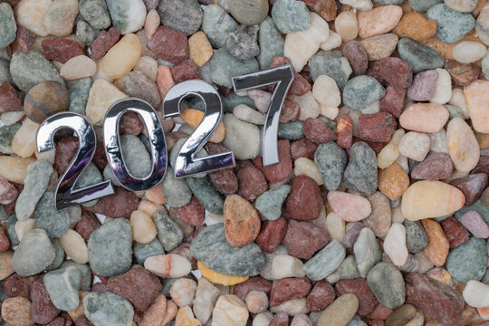 New year concept, silver 2027 numbers on wet multi-colored stone background.
