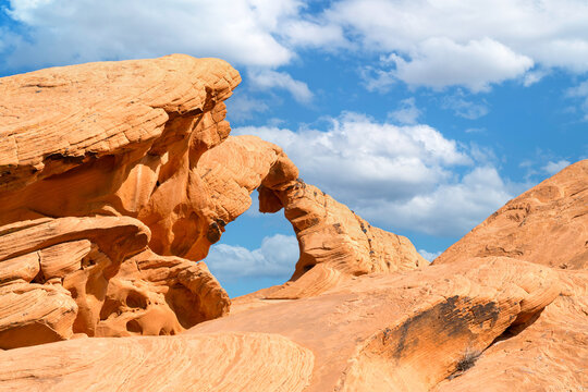 Natural stone arch in the Valley of Fire, Near Las Vegas, Nevada. Famous for its incredible red rock formations, shown here against a clear blue sky background. Space for your text.