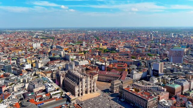 Aerial view of Milan Cathedral and Piazza del Duomo in Italy, with people on the square, the Galleria Vittorio Emanuele II dome, the Royal Palace, Torre Velasca and rooftops of the centre.
