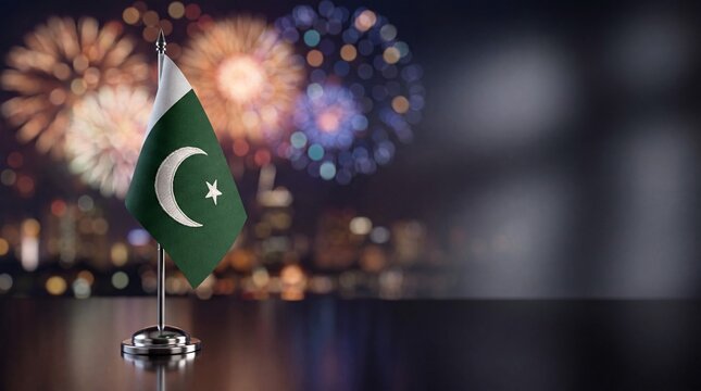 Pakistani Table Flag on Reflective Surface with Colorful Fireworks in Night Sky Celebrating Independence Day and National Pride
