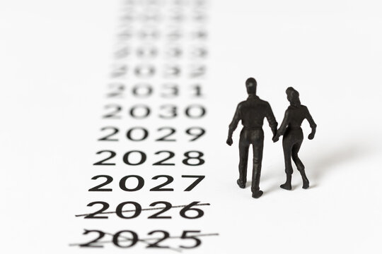 miniature couple walking towards new year 2027 leaving crossed out past years behind