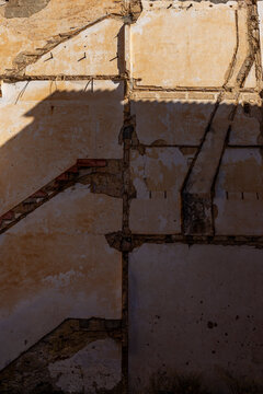 Weathered concrete wall with exposed aggregate, geometric shadows and textured surface, photographed as an abstract architectural detail