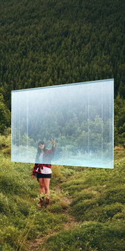 Woman reaching toward floating transparent portal on forest trail. Concept of digital interaction and innovation for technology campaigns, outdoor branding and future advertising.