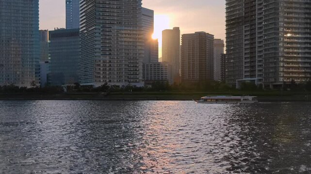 ビルの間に夕陽が沈む都市の風景。