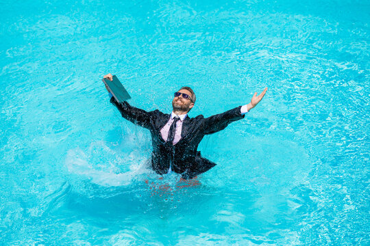 Remote working. Summer business vacation. Funny crazy businessman rest in formal wear in pool. Businessman in suit with laptop in swimming pool. Crazy business man summer vacation. Holiday work
