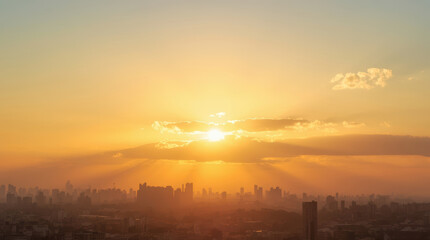 Fototapeta premium Golden sunrise over urban skyline with warm light rays and hazy cityscape
