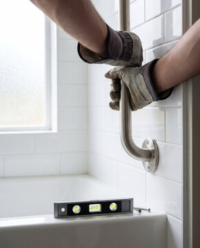 Contractor testing grab bar anchor strength with visible pull tension and spirit level