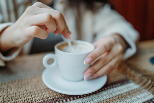 Woman stirring morning coffee in a white cup