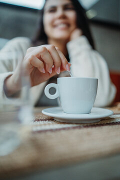 Woman stirring coffee in a cafe enjoying morning break