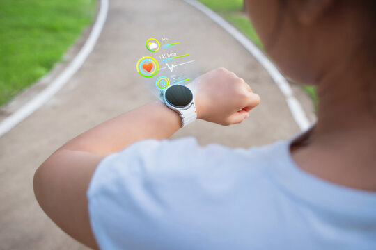 The young woman monitors her heart rate via an application on her smartwatch. The concept involves exercising for health, such as running and walking.