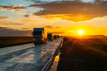 Obraz premium A truck is driving down the highway during an orange sunset, with the sun's rays