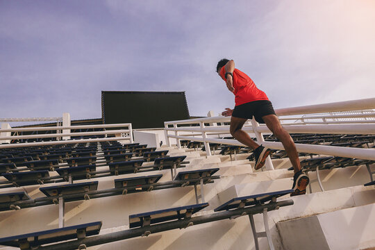 A man runner running sprinting up stairs at stadium. Fit runner fitness runner during outdoor workout. Selected focus