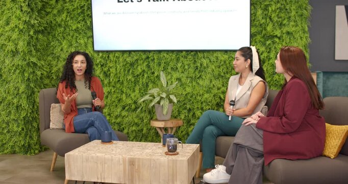 Female panelists prompted by Let's Talk About AI slide exchanging mics, sharing AI ideas in lounge