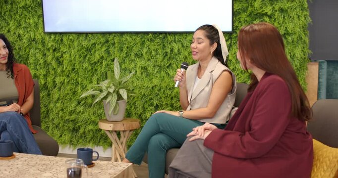Three female panel starting AI discussion after display prompt in green lounge, passing mics