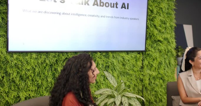 Female panelists responding to screen showing Let's Talk About AI, speaking with mics in lounge