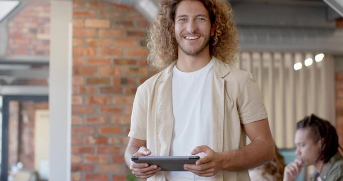 Diverse male team, camera zooming out, man holding tablet and sharing update in office with laptop