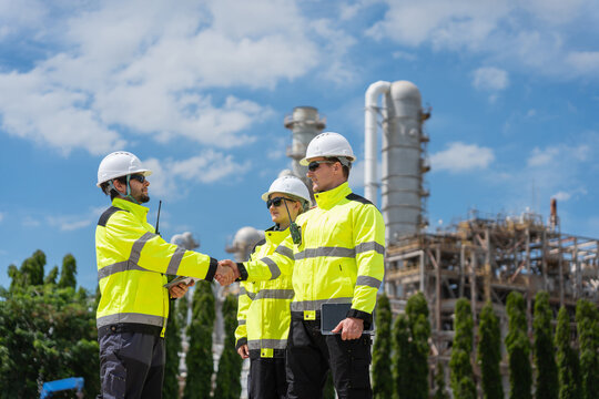 Industrial engineers team shaking hands at oil refinery plant facility, Supervisors agreeing on project at oil and gas plant, Worker team in safety gear celebrating partnership at industrial site