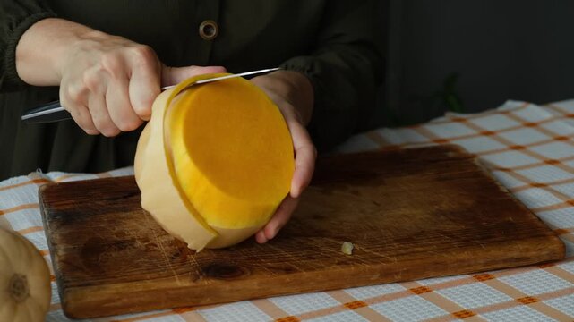 Female hands peeling pumpkin. Preparing autumn food. Cooking pumpkin soup or cake.