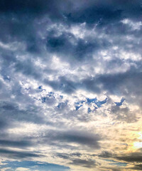 Obraz premium Dramatic Dark Storm Clouds with Sunlight Breaking Through Overcast SkyA dramatic overcast sky filled with dark storm clouds as sunlight breaks through the cloud cover.