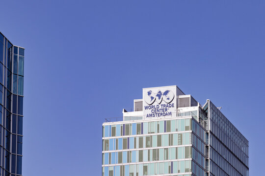 Amsterdam, Netherlands, May 23, 2026. The top of the World Trade Center WTC Amsterdam skyscraper building featuring its distinctive blue globe logo and text against a clear blue sky.