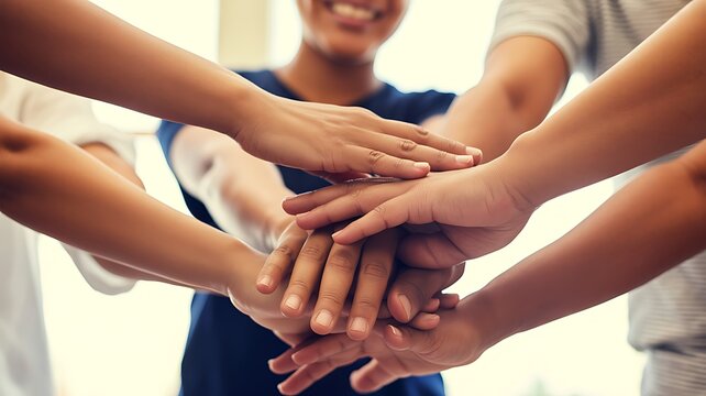 Diverse group of people showing unity and teamwork with hands stacked in a collective high-five gesture. 