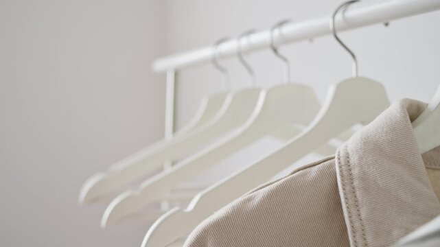 Woman neutral garments hanging on white hangers present elegant clothing arrangement for retail or home. Clothing display, apparel presentation, fashion showcase encourage organized storage. 4K