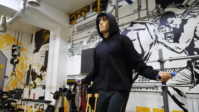 Young sportsman skipping with a jump rope at modern gym. Strong sporty man exercising in fitness centre. Athletic guy doing cardio at sport club. Concept of healthy and active lifestyle. Slow motion
