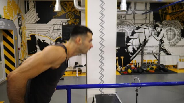 Muscular sportsman doing push ups on parallel bars at modern gym. Young athlete exercising at sport club. Strong sporty man training hard indoor. Concept of active sportive lifestyle. Close up Slow mo
