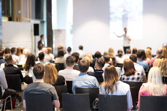 Speaker presenting at a business conference. Audience listening to a professional seminar.