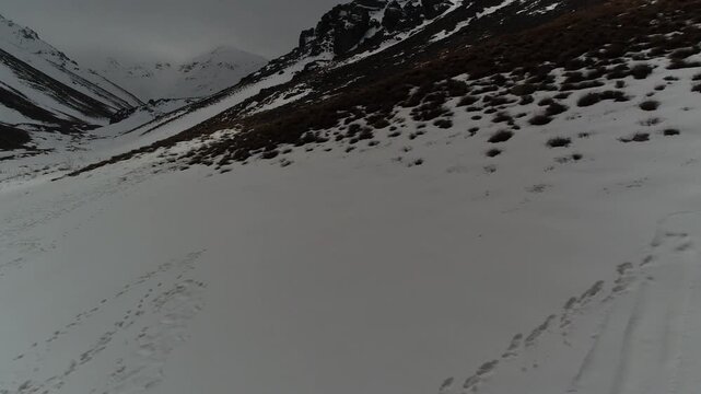 Beautiful close-up aerial tracking shot moving over a smooth pristine white snow blanket on a steep mountain slope, capturing minimalist winter textures and frozen nature details asset.
