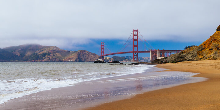 iconic golden gate bridge with waves crashing onto baker beach in san francisco california