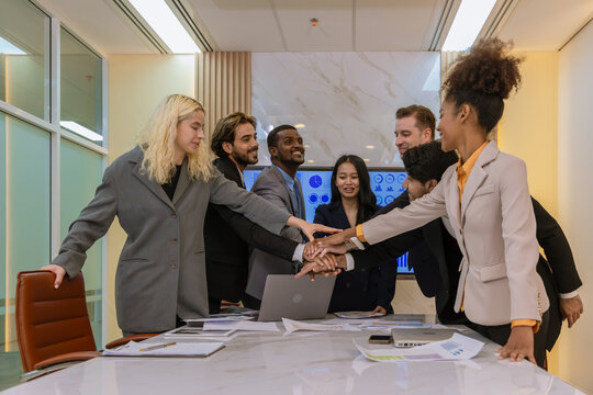 Diverse colleagues gather in brainstorm discuss statistics together. Group of people colleagues gather showing unity with their hands together. 