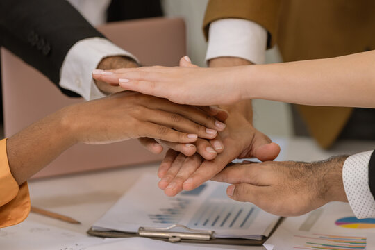 Diverse colleagues gather in brainstorm discuss statistics together. Group of people colleagues gather showing unity with their hands together. 