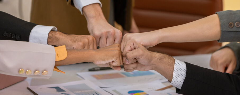 Diverse colleagues gather in brainstorm discuss statistics together. Group of people colleagues gather showing unity with their hands together. 