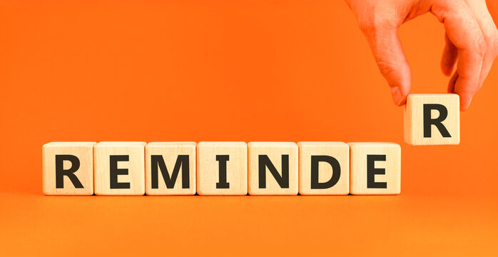 Reminder word symbol. Concept word Reminder on beautiful wooden blocks. Beautiful orange background. Businessman's hand. Business support help reminder word concept. Copy space.