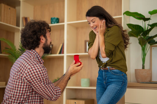 Man proposing marriage with engagement ring surprising woman