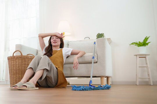 Tired woman rests after mopping the floor at home, reflecting fatigue, household responsibility, recovery, and the balance of modern domestic life.