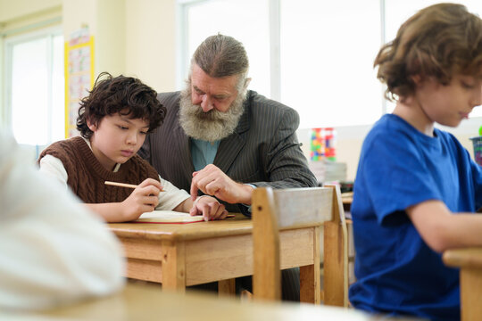 Dedicated teacher provides one-on-one guidance to a young student writing in class, promoting confidence, focus, and academic growth in a supportive learning environment.