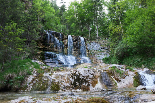 Weissbach waterfall in Schneizlreuth, Germany during summer season. Fresh mountain water splashing on rocks in forest in German Alps region. Natural attraction and popular travel destination.