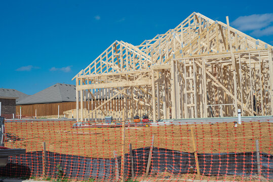 Rising residential development near Dressage Ln highlights evolving neighborhood character. Workers install roof rafters while foundation waits for exterior cladding beside home. Aubrey, TX