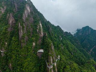 Obraz premium A high angle view showing the lush green peaks and winding cliff side walking paths of Sanqingshan Mountain located in Jiangxi province of China on a cloudy day