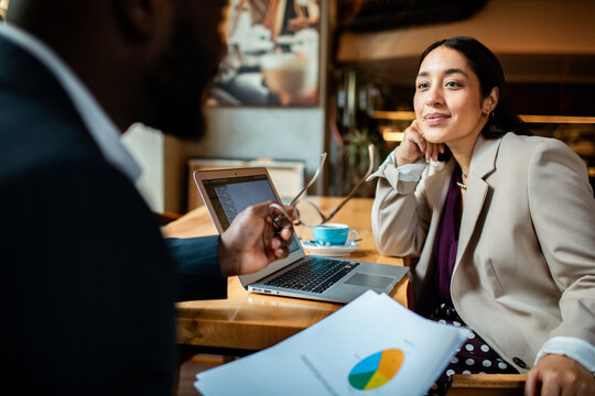 Two business professionals meeting in a cafe with laptop and charts