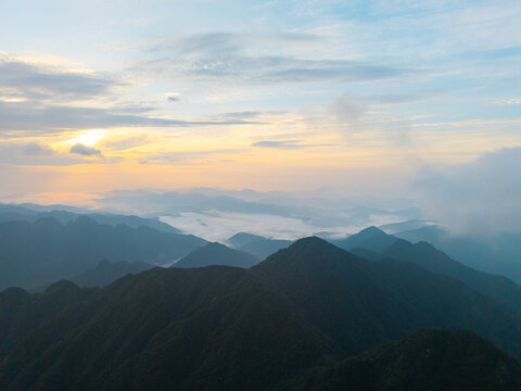 The sun rises over the scenic peaks of Sanqingshan Mountain located in the Jiangxi province of China as clouds drift between the rolling forested hills