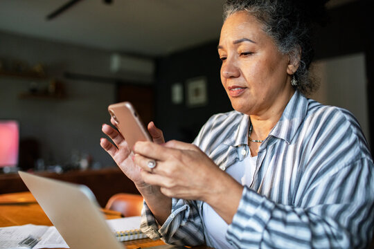 Woman using smartphone for online banking at home