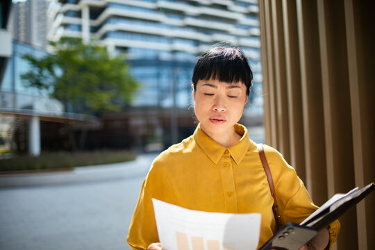 Focused businesswoman reading financial report in modern city