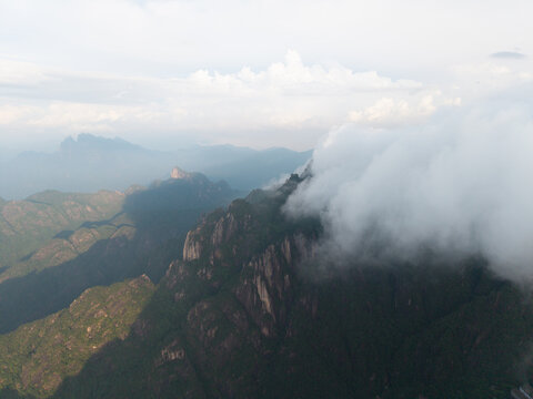 A beautiful aerial view captures the majestic granite peaks of Sanqingshan Mountain in Jiangxi China as thick white clouds roll over the rugged rocky landscape during the day