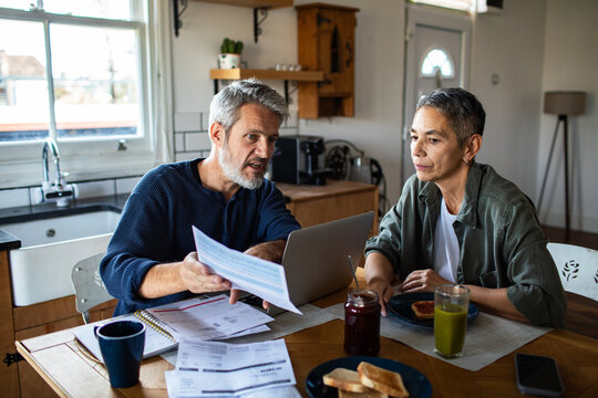 Mature couple reviewing bills at kitchen table